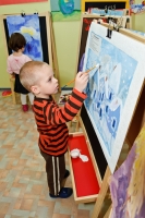 Ребёнок рисует гуашью на мольберте.
