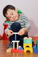 Ребёнок строит домик из деревянных кубиков.